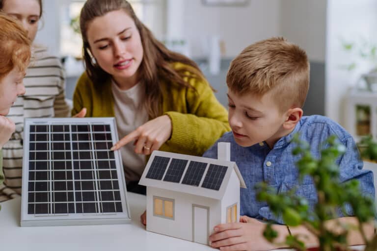 young teacher with solar panel learning pupils about solar energy.
