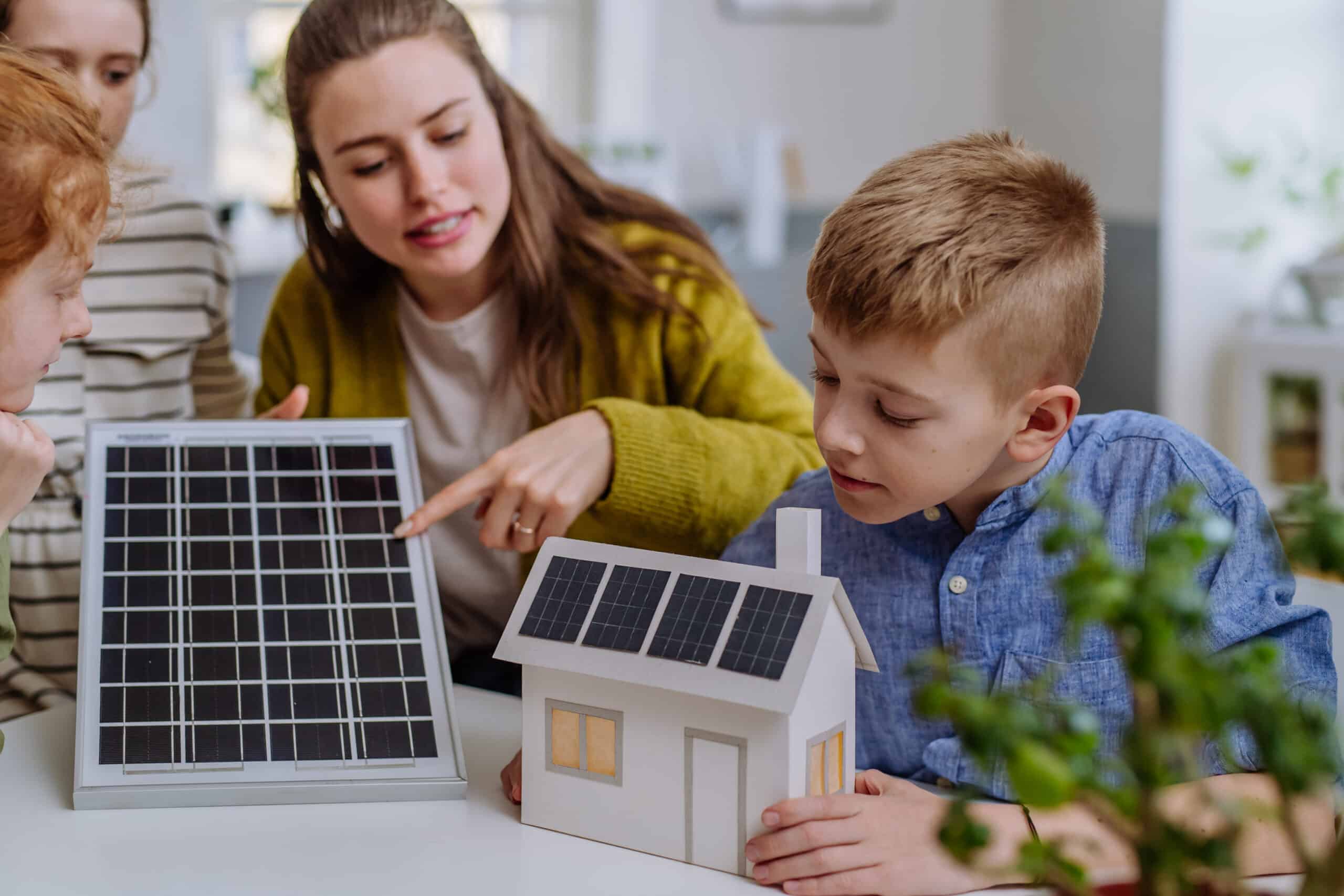 young teacher with solar panel learning pupils about solar energy.