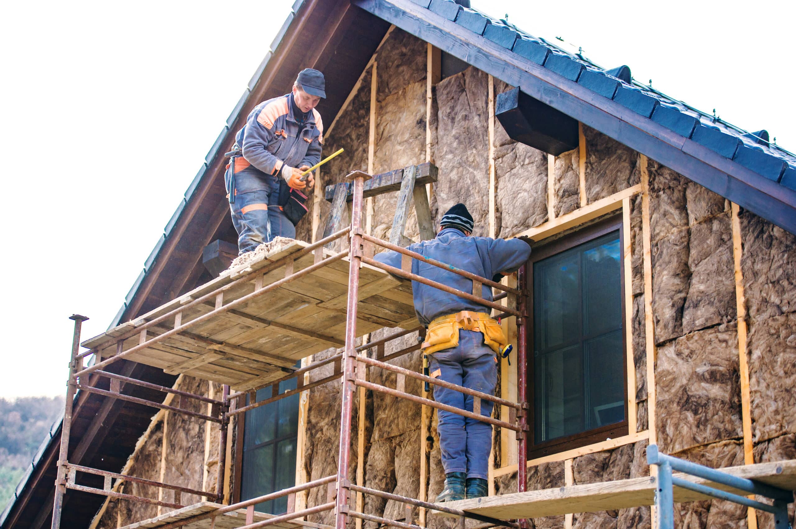 construction workers thermally insulating house facade with glass wool.