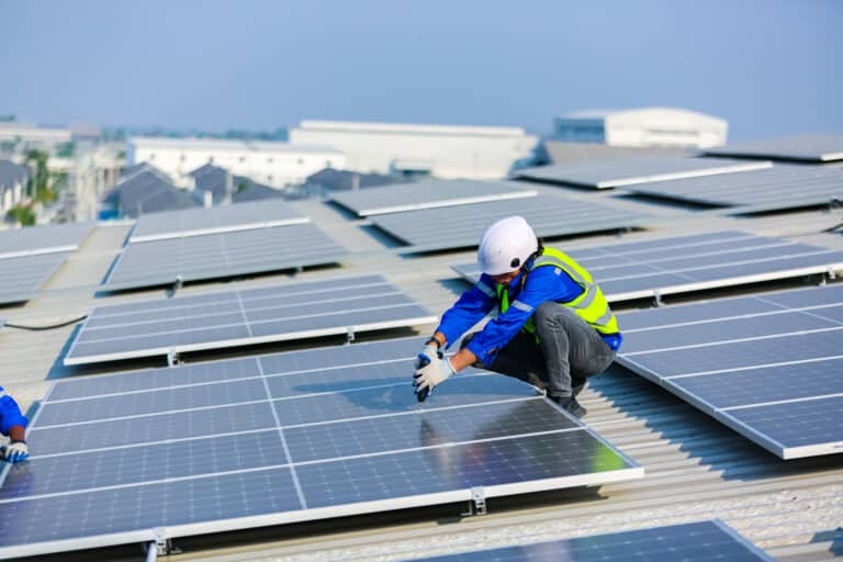 solar panel installer installing solar panels on roof of warehouse