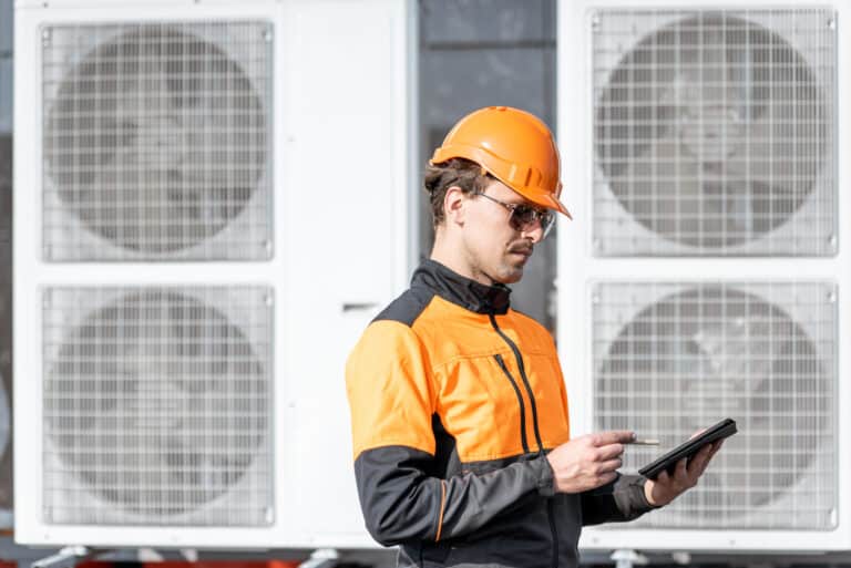 workman servicing air conditioning or heat pump with digital tablet