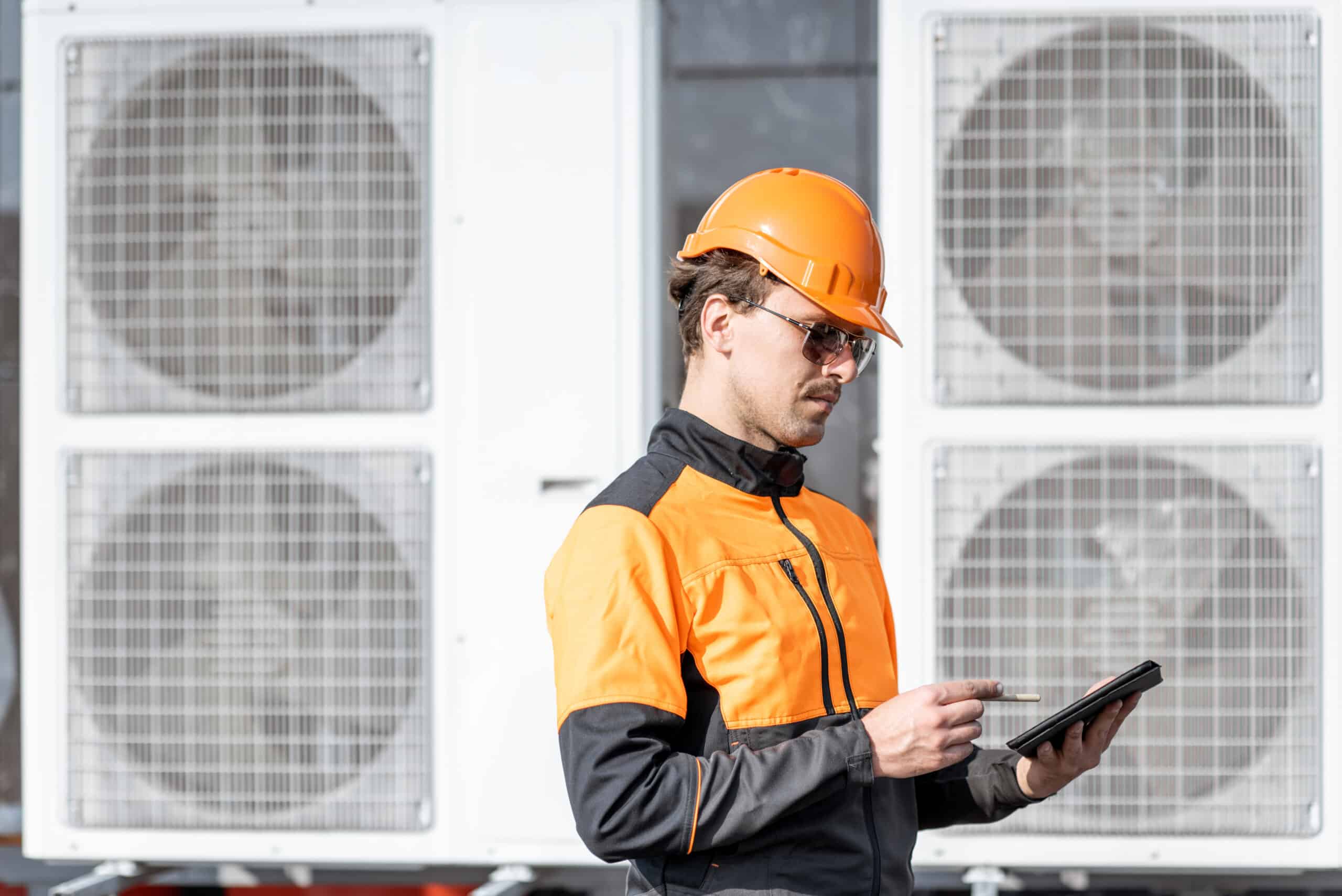 workman servicing air conditioning or heat pump with digital tablet
