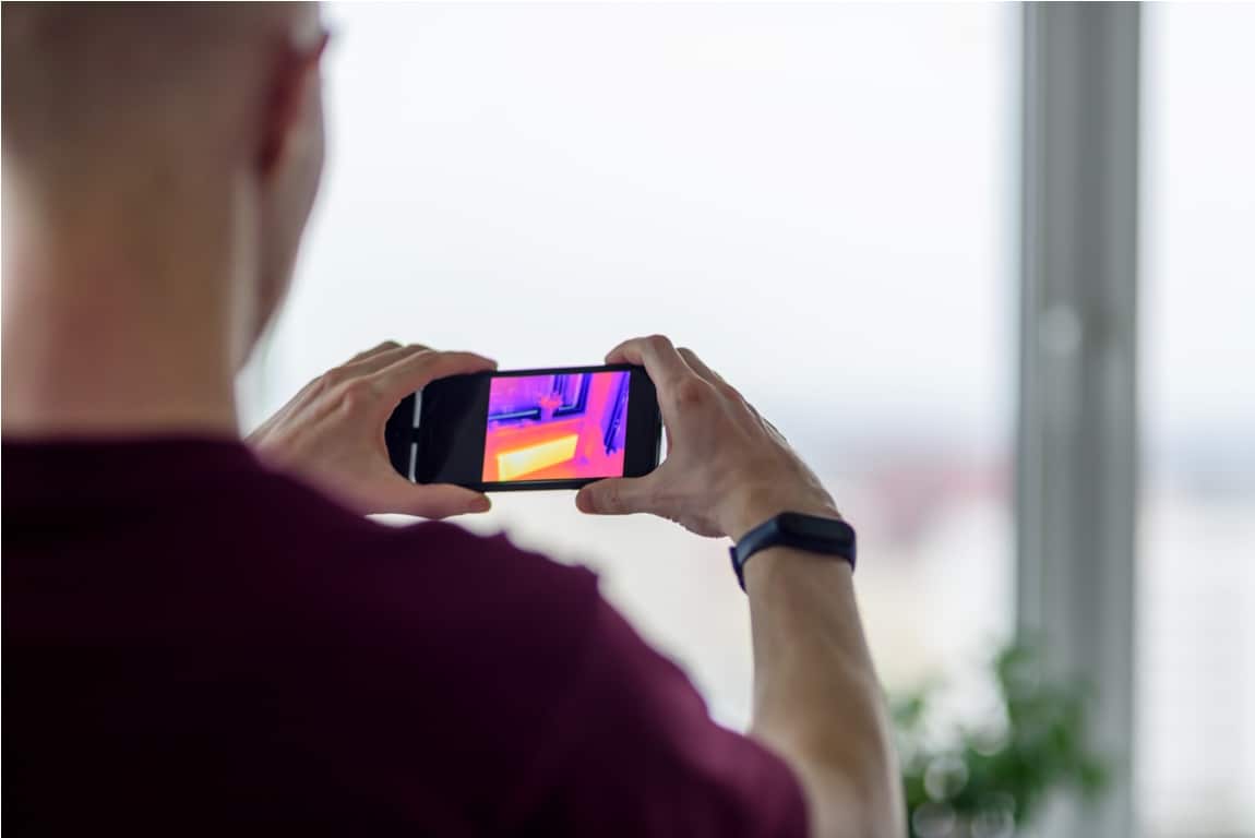 person doing thermal scanning of apartment