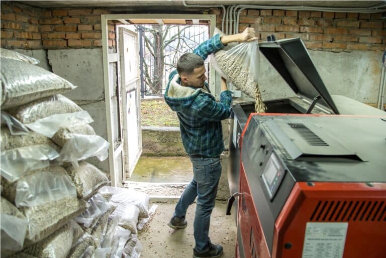 the man loads the pellets in the solid fuel boiler, economical heating