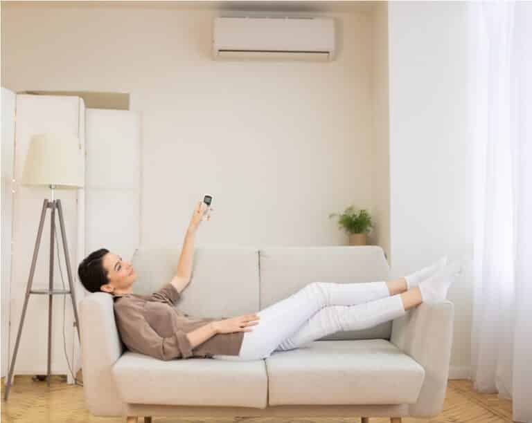 young woman switching on air conditioning at her h 2022 12 16 09 00 49 utc