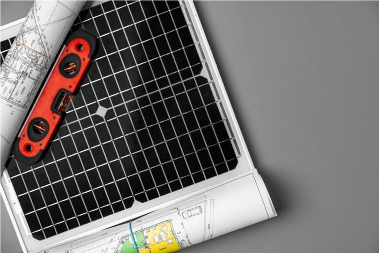 architectural blueprints and solar panel on table