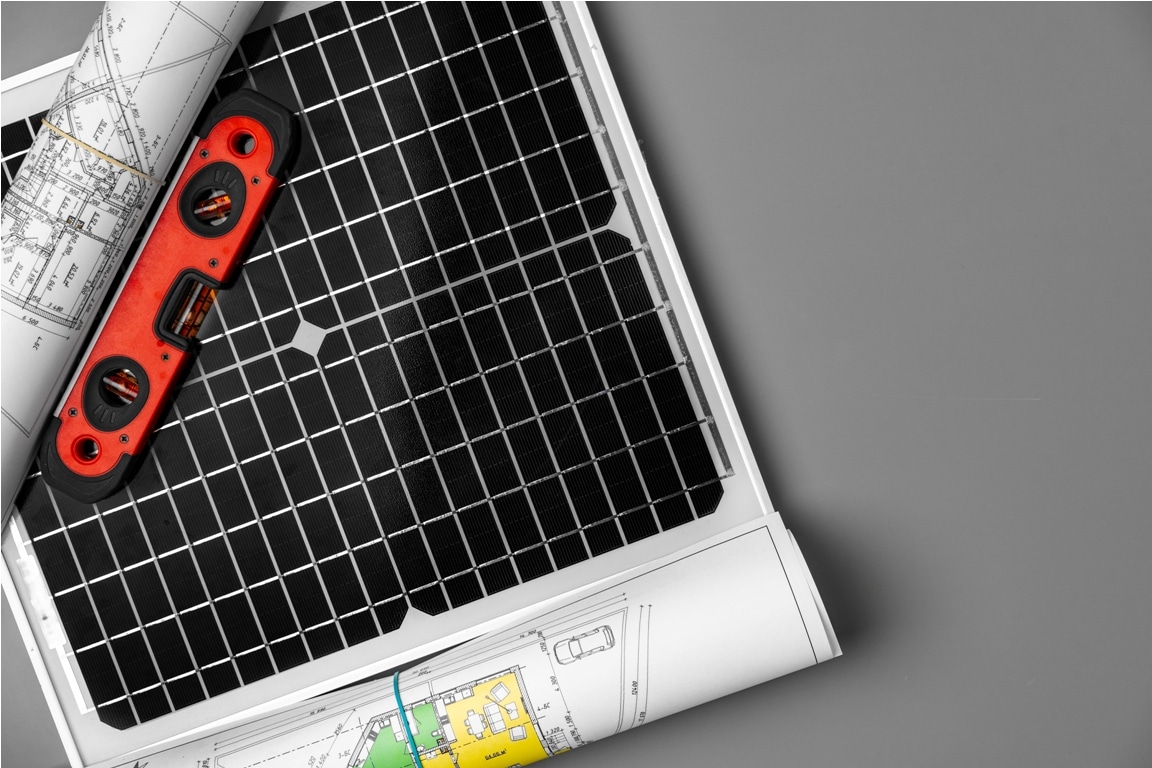 architectural blueprints and solar panel on table