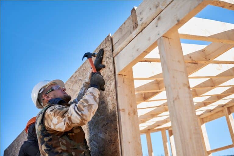 carpenter hammering nail into osb panel while buil 2022 08 19 07 10 14 utc