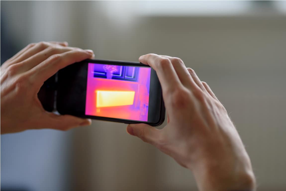 person doing thermal scanning of apartment